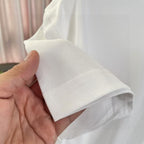 White Louis Vuitton T-shirt sleeve cuff and hem seam, held by hand