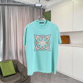 Turquoise crewneck T-shirt with large multicolor geometric emblem graphic on front