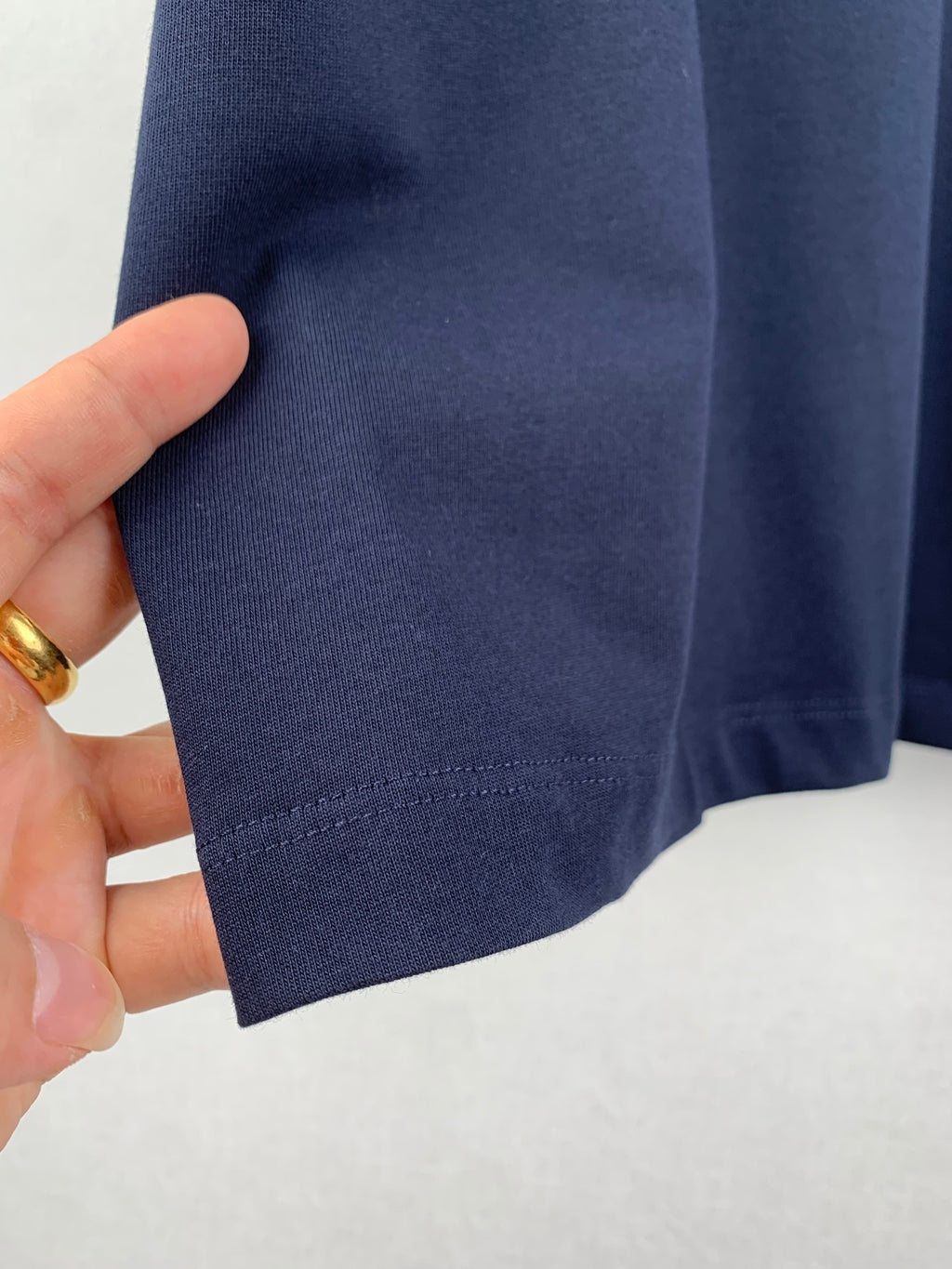 Navy T-shirt sleeve cuff and hem stitching, close-up