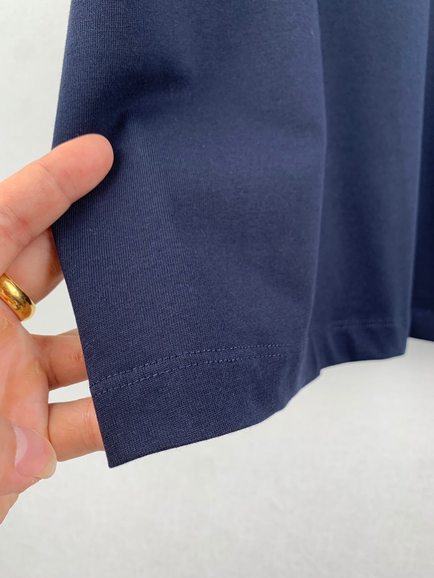 Navy T-shirt sleeve cuff and hem stitching, close-up