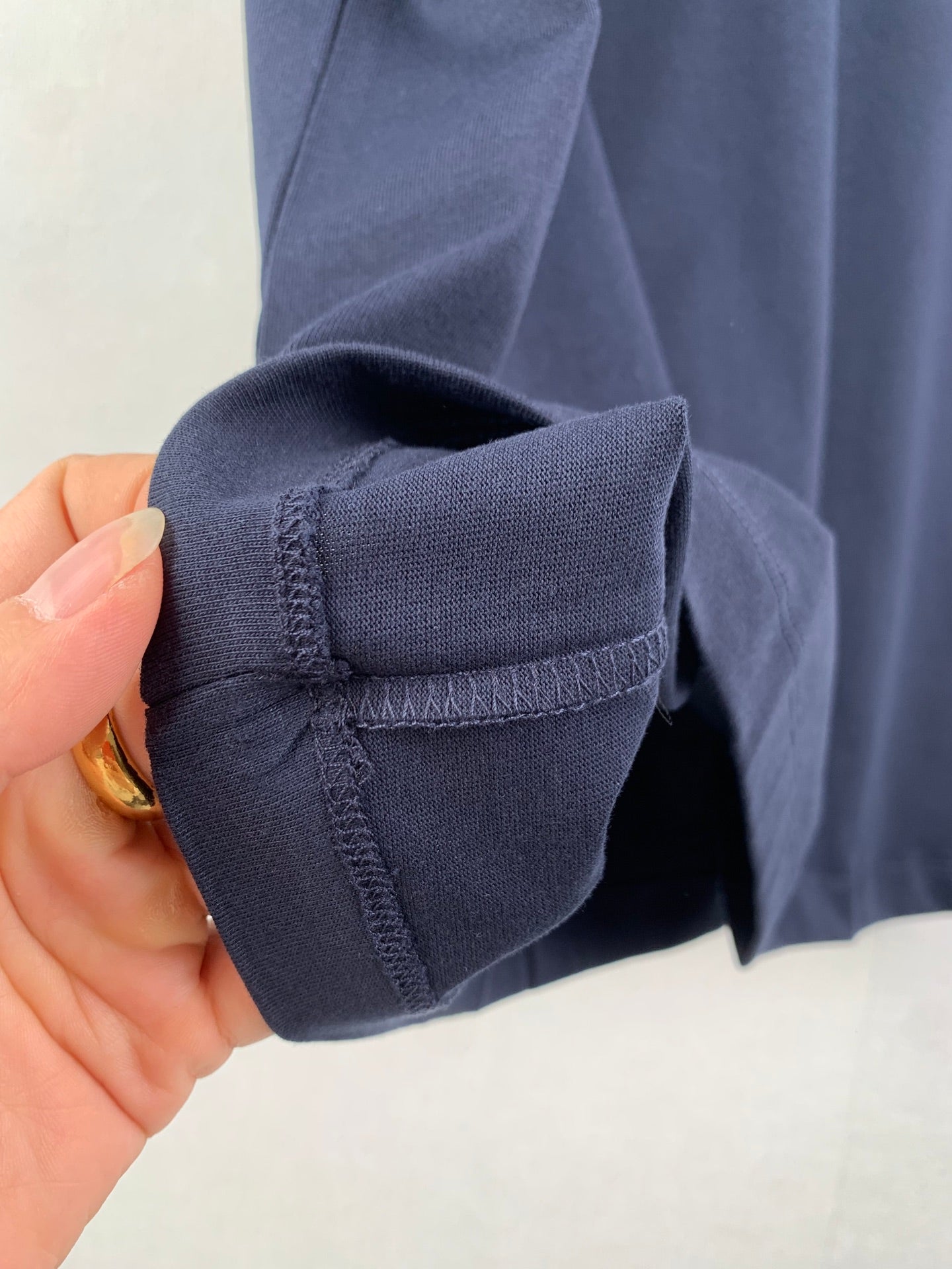 Navy T-shirt sleeve cuff detail held in hand