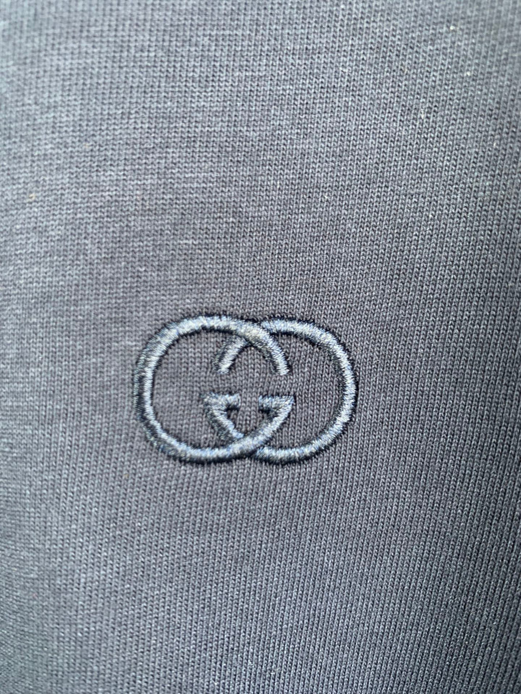 Gucci double-G logo embroidered on blue T-shirt fabric close-up