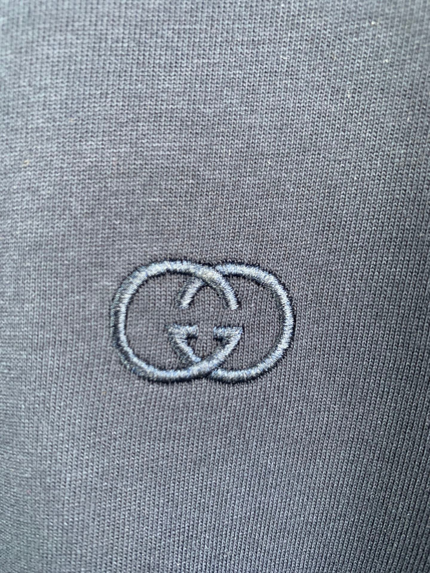 Gucci double-G logo embroidered on blue T-shirt fabric close-up
