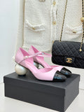 Pink leather flats with black patent toe cap and bow strap, on display box