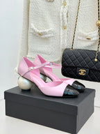 Pink leather flats with black patent toe cap and bow strap, on display box