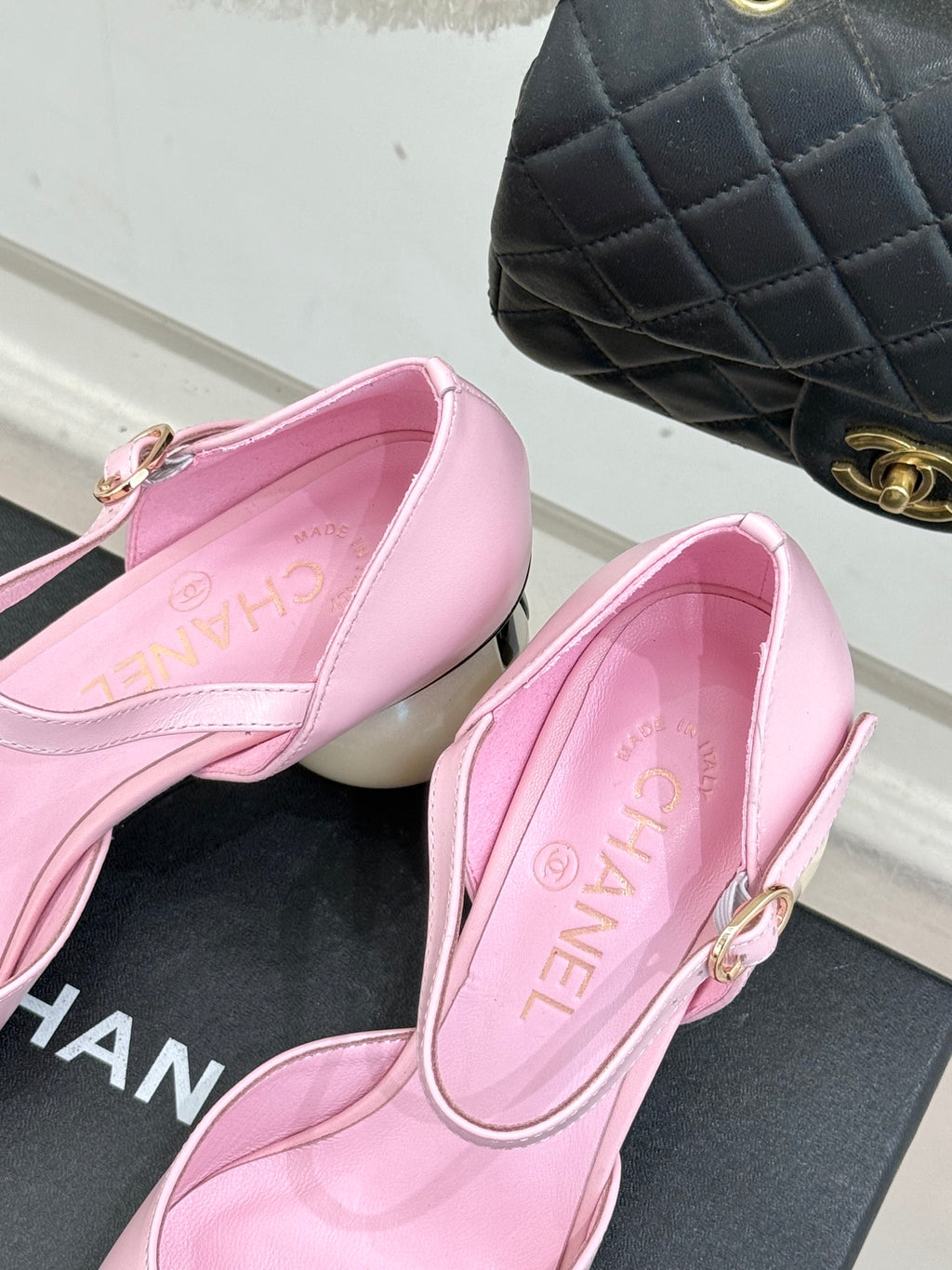 Pink flats close-up with gold buckle ankle strap and black patent toe cap