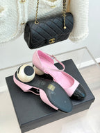 Pink slingback flats with black patent toe cap, paired on black display box