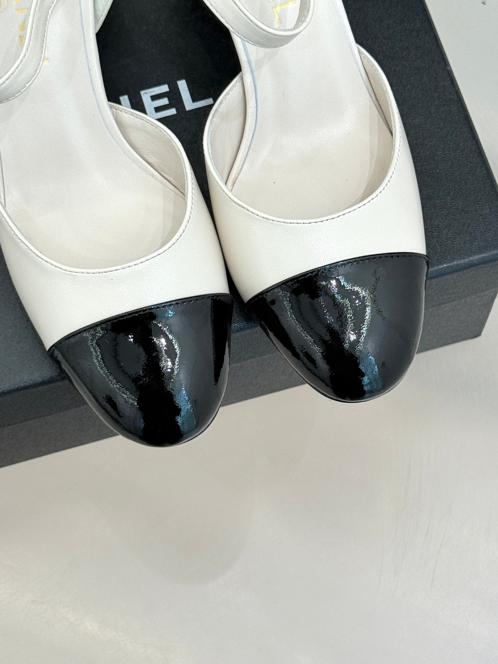 Chanel slingback pumps close-up: white uppers with black glossy toe