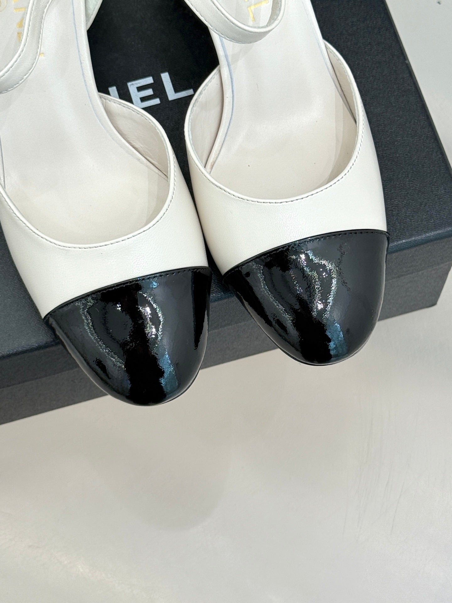 Chanel slingback pumps close-up: white uppers with black glossy toe