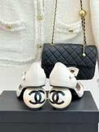 Chanel white slingback pumps with black patent toe caps, front view on box