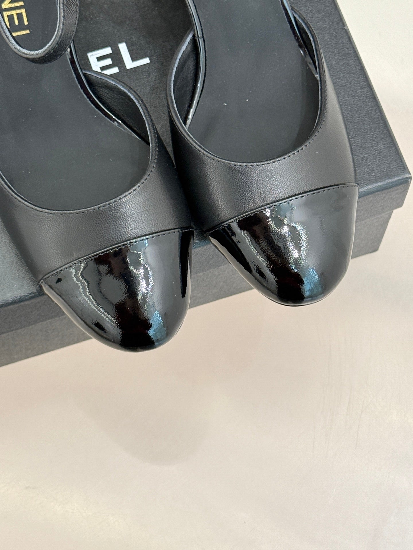 Close-up of black pointed flats with glossy toe and slim ankle cutout