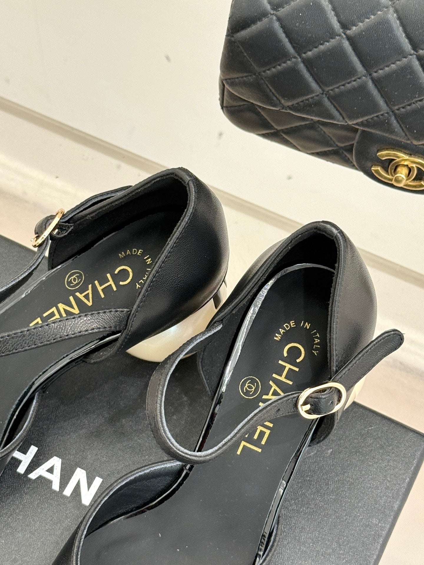 Black flats with pointed toe, slingback strap, and gold-tone CHANEL logo