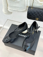 Black slingback flats with pointed toe, ankle strap, and small buckle detail