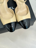 Beige flats with black patent toe cap and bow strap, close-up
