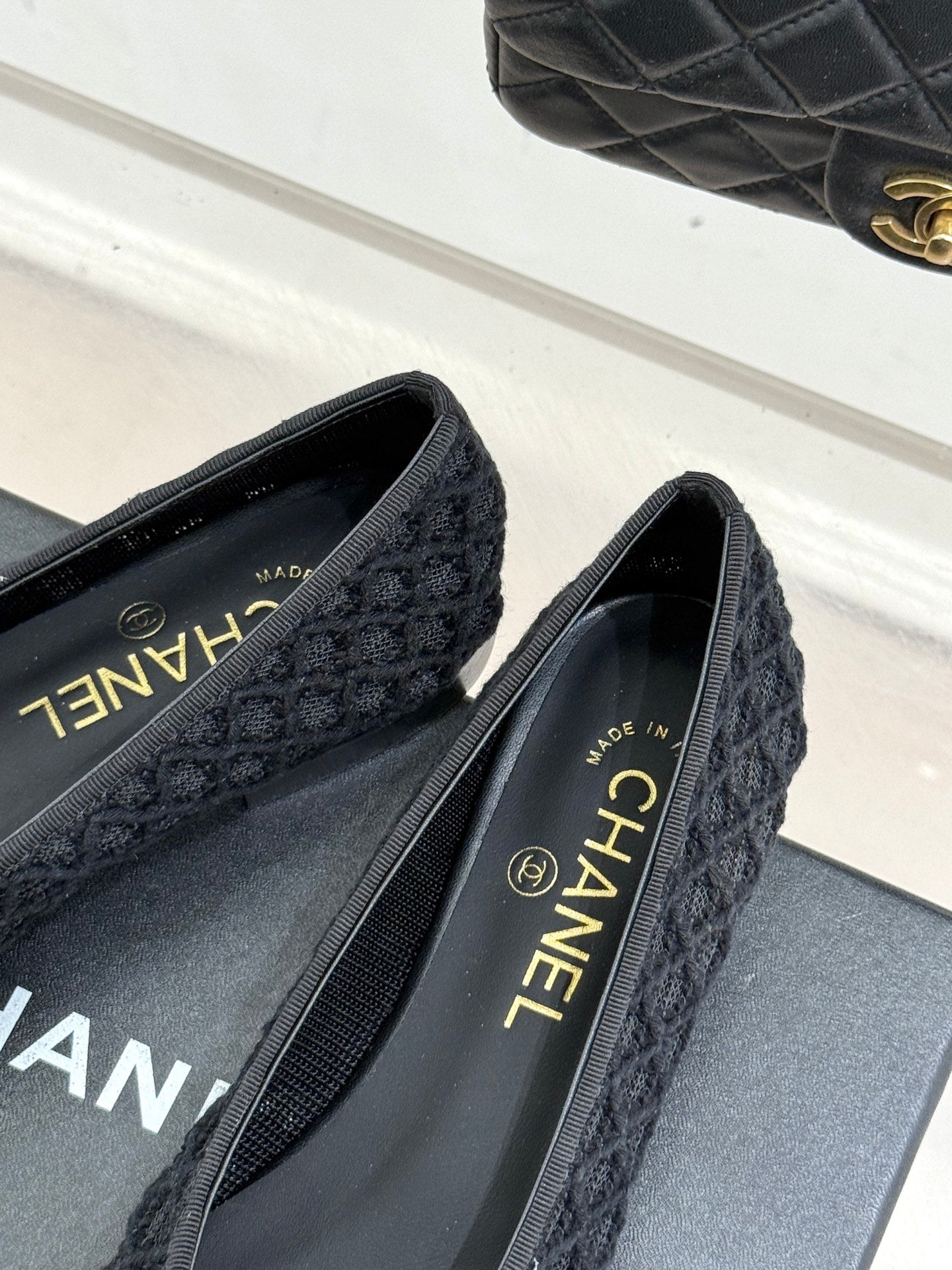 Close-up of dark textured ballet flats with Chanel insole text and heel detail