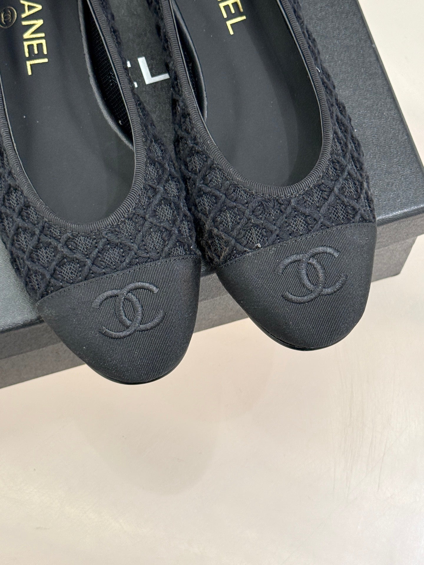 Close-up of two dark textured ballet flats with CC logos on toe