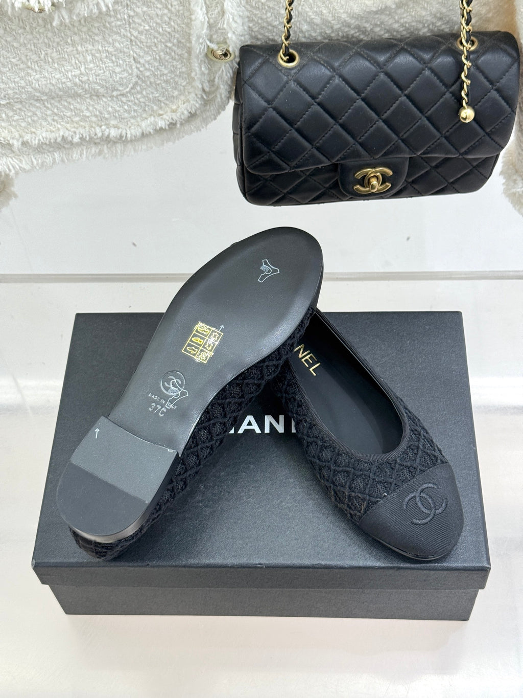 Dark textured ballet flats with CC logo on toe above grey shoebox