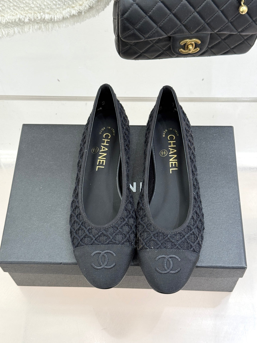 Pair of dark textured ballet flats, side view with CC logo on toe
