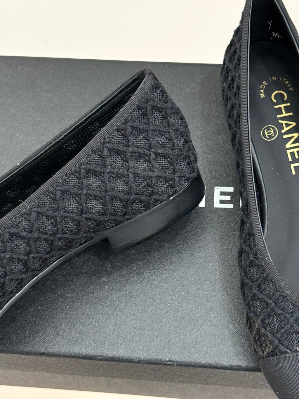 Close-up of dark textured ballet flat upper and insole on grey box