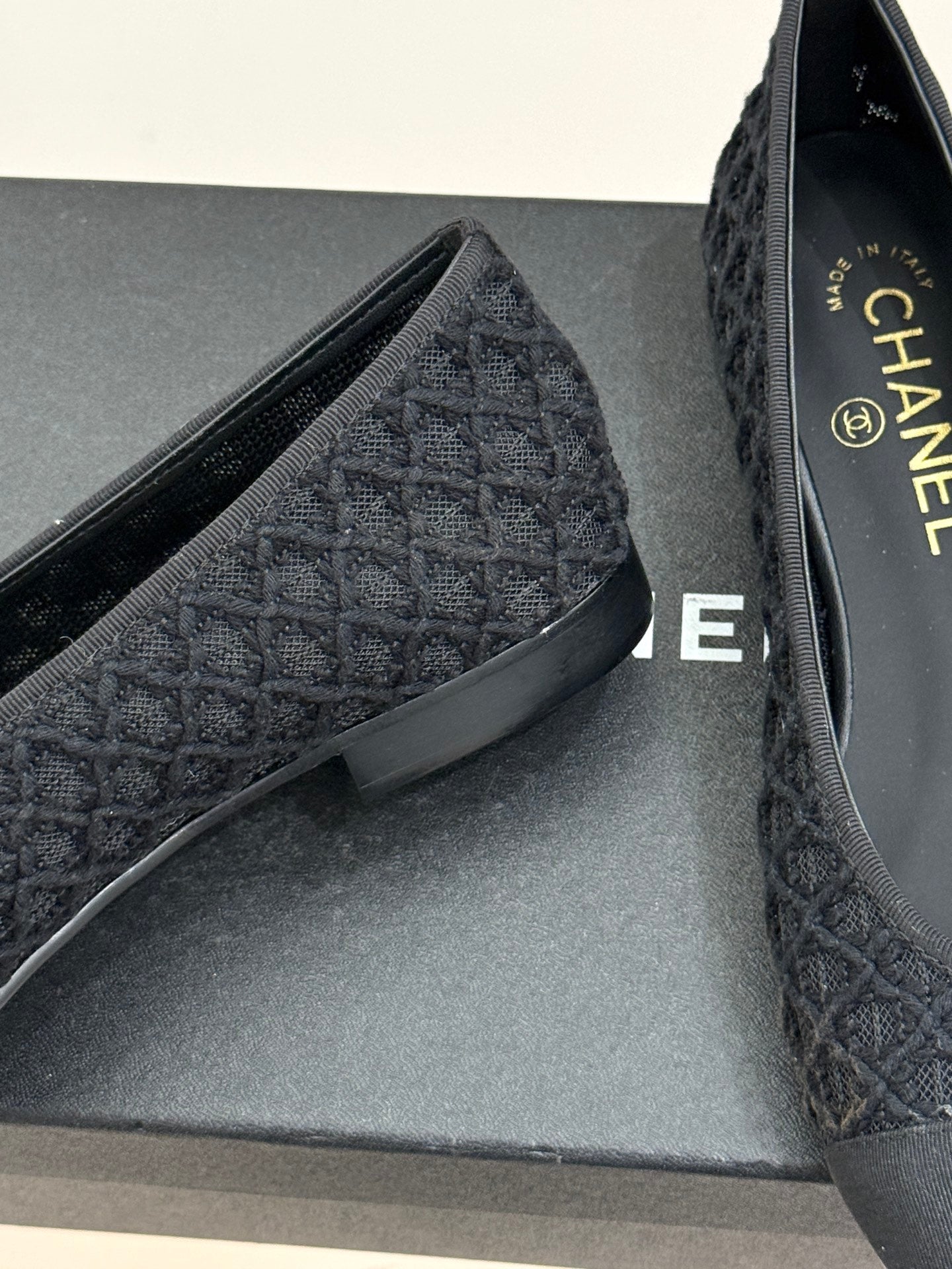Close-up of dark textured ballet flat upper and insole on grey box