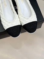 White lace ballet flats with black toe caps and CC logo, close-up on shoebox