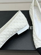 White lace ballet flat with textured vamp and black toe cap, on shoebox