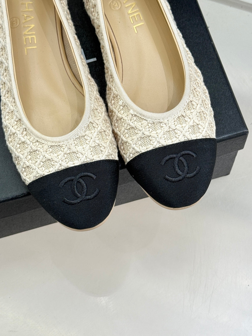 Chanel ballet flats close-up: cream upper with dark navy CC logo toe caps