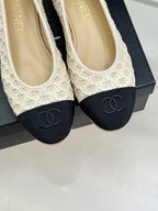Chanel ballet flats close-up: cream upper with dark navy CC logo toe caps