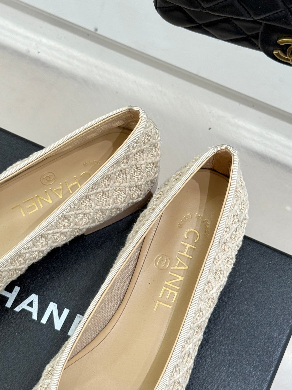 Chanel flats close-up with cream textured uppers and dark navy toe caps