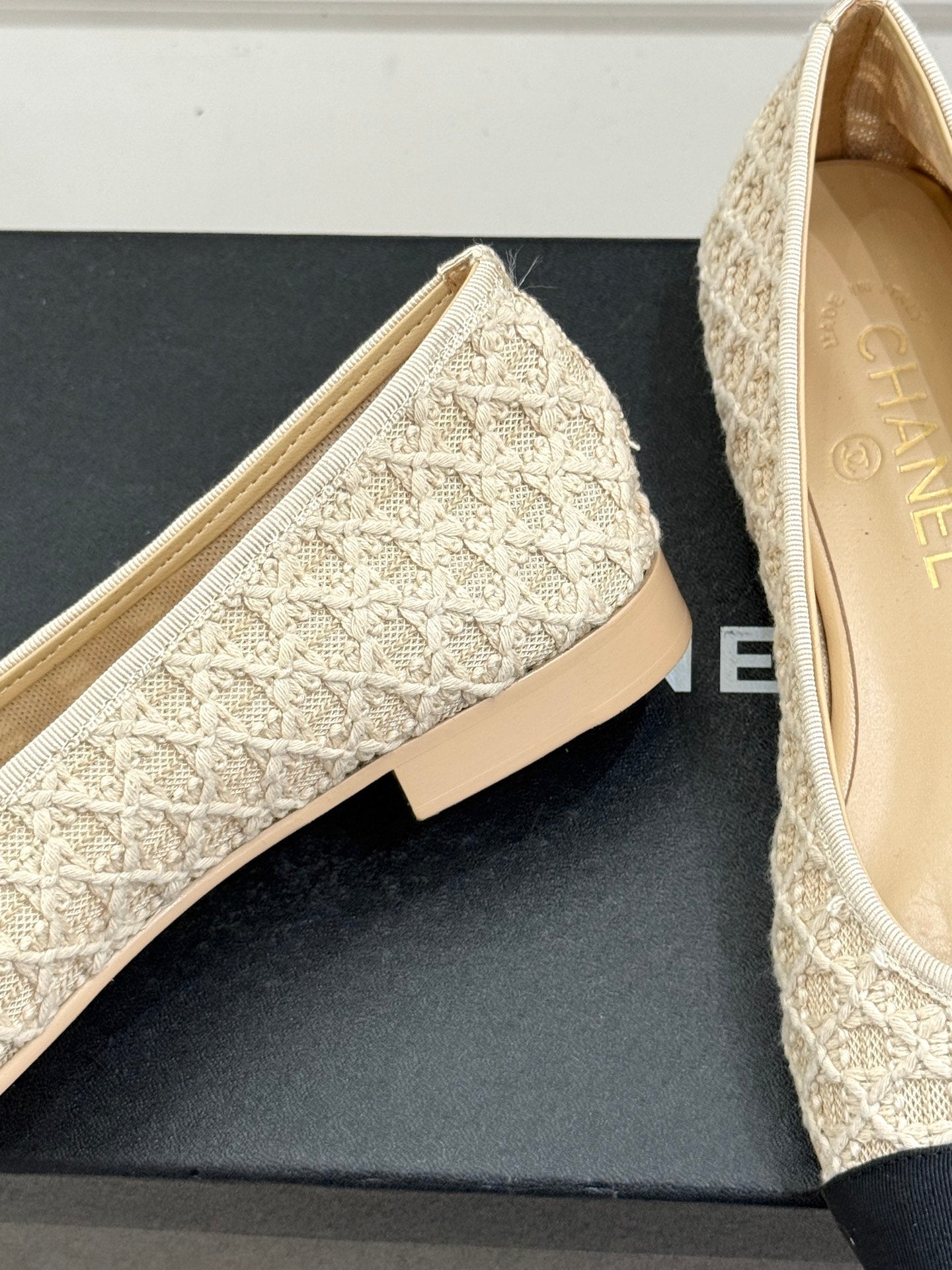 Chanel flats showing cream lace-texture upper and dark navy toe caps near heel