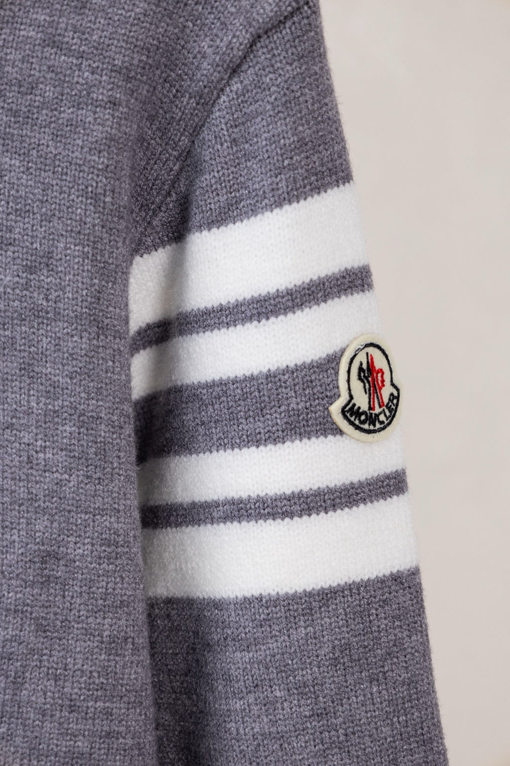 Moncler grey knit sweater sleeve showing white and dark striped trim and patch