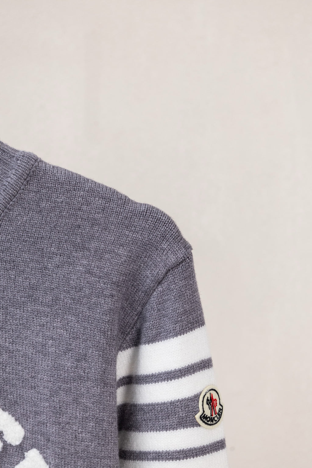 Moncler grey sweater sleeve with white striped band and round Moncler patch