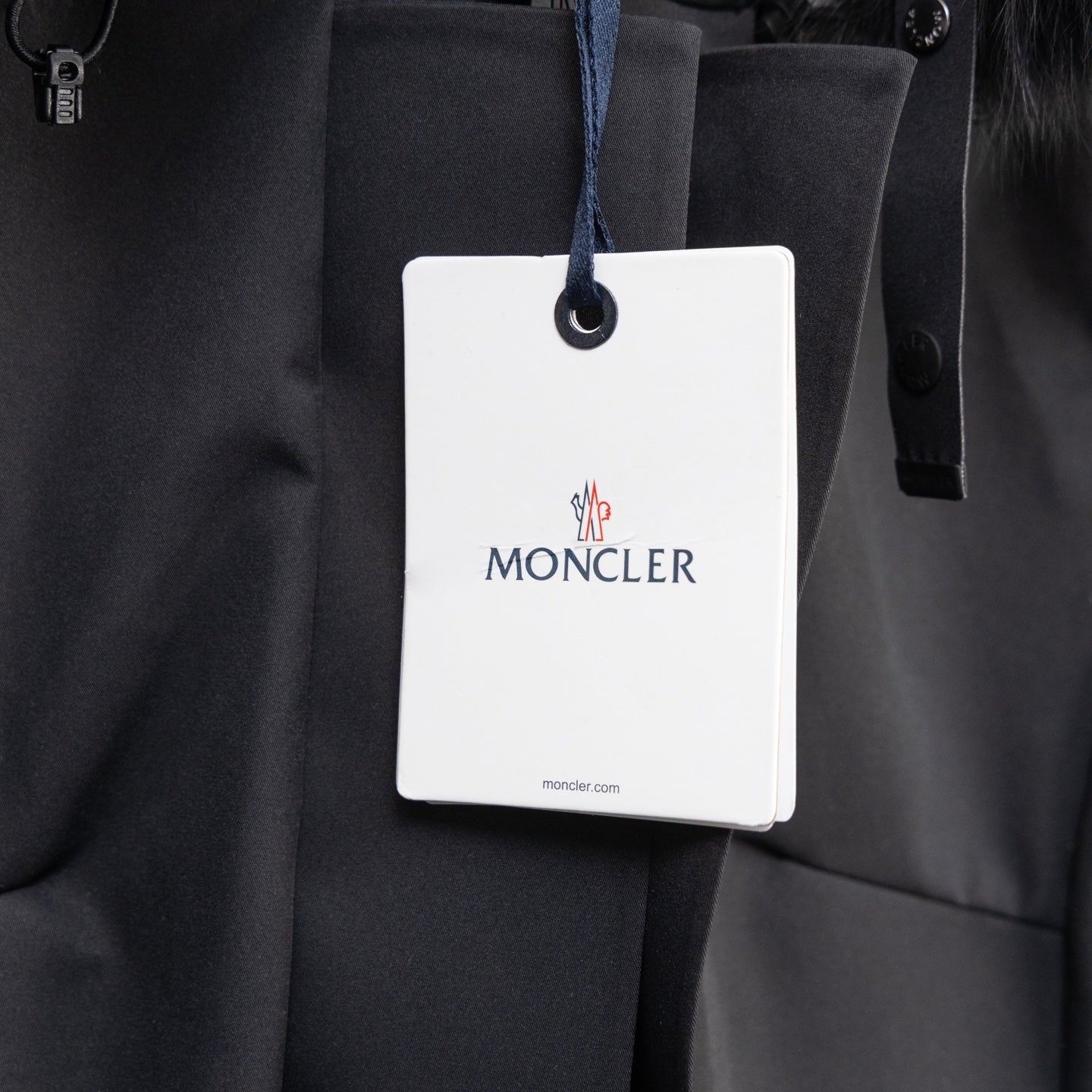 Moncler parka front with hanging brand tag and buttoned placket