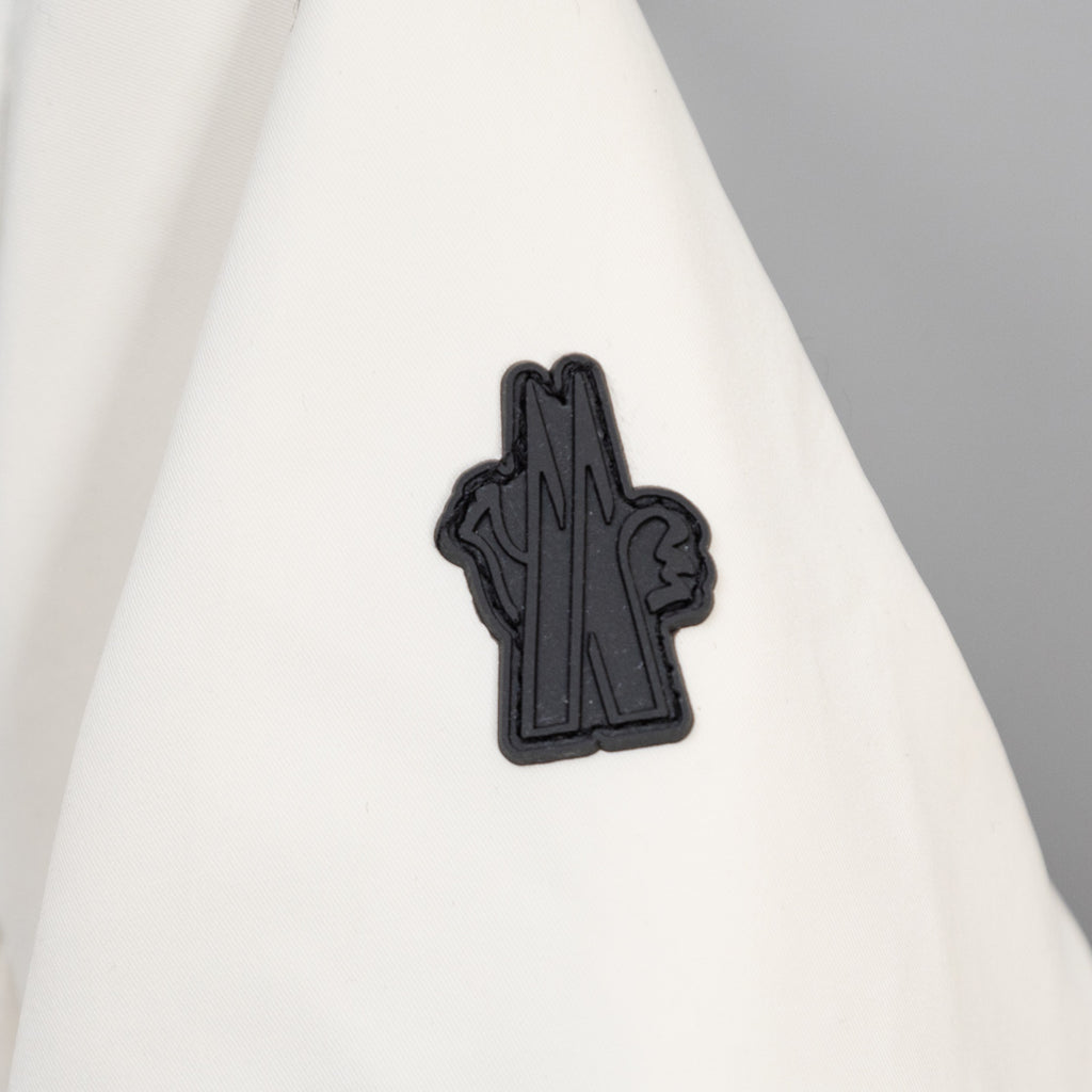 Moncler long coat with small black logo patch on white fabric