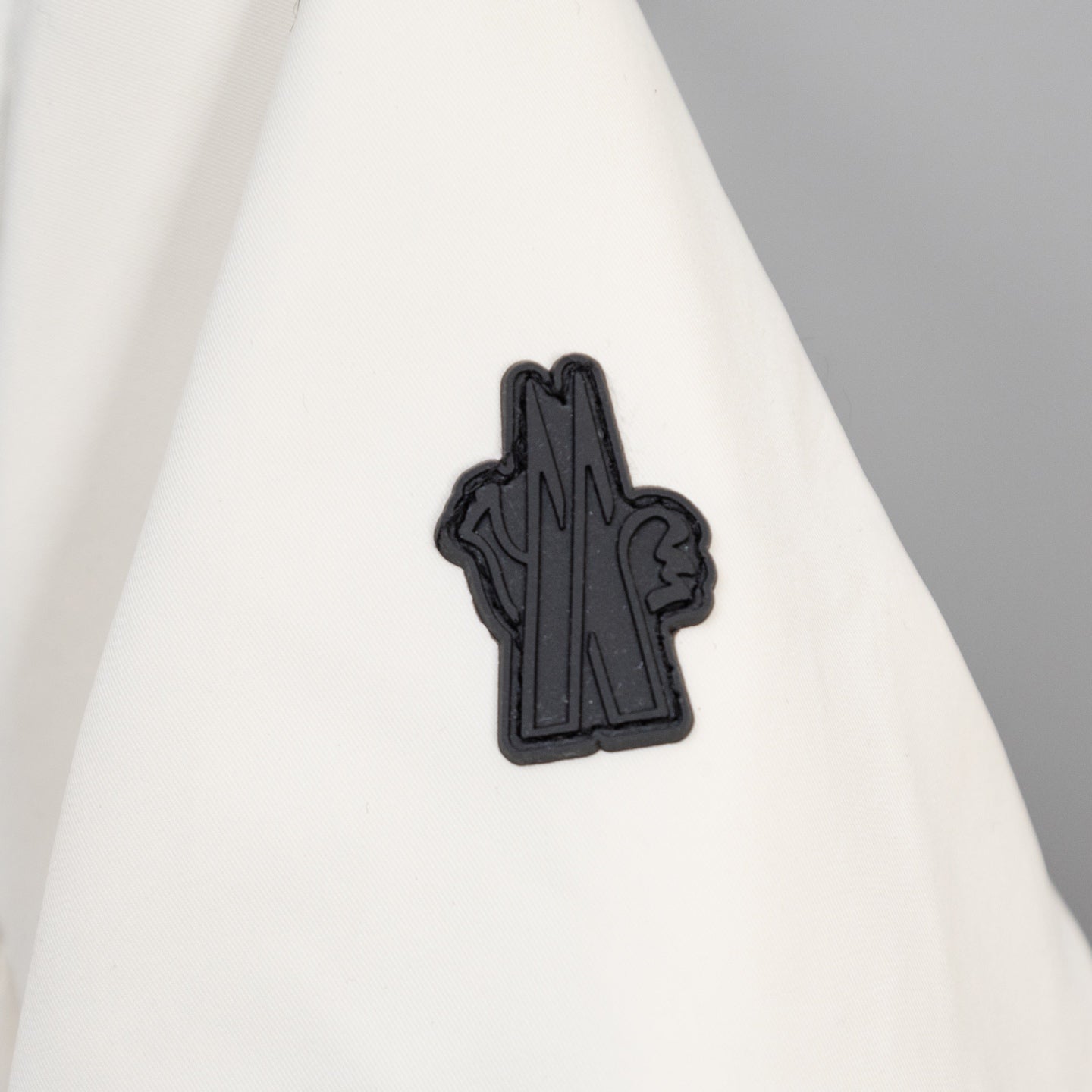 Moncler long coat with small black logo patch on white fabric