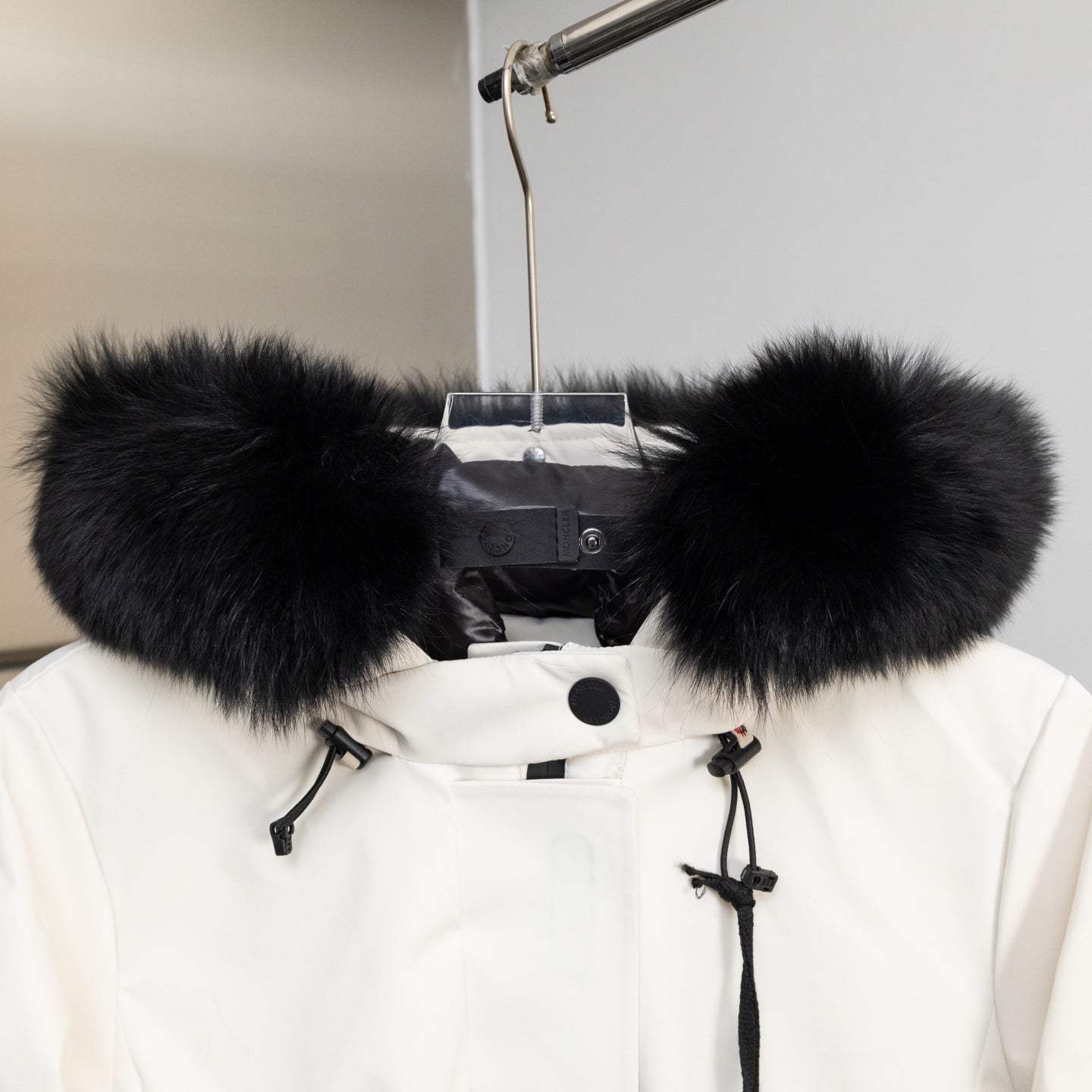 Moncler white jacket hood with large black faux-fur trim and drawstring ties