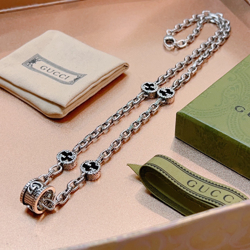 Silver-toned charm necklace with black enamel quatrefoil links and toggle clasp