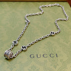 Silver-toned chain necklace with black enamel quatrefoil charms and toggle clasp