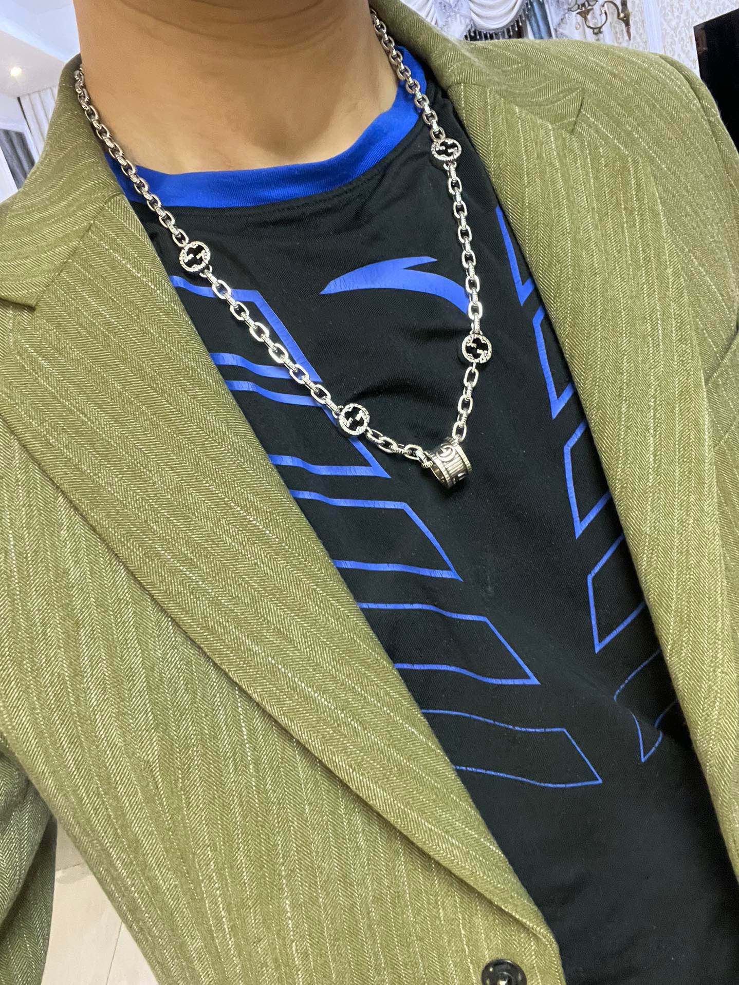 Silver-toned chain necklace with black enamel motif links on a blazer model