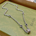 Silver-toned chain necklace with black enamel link charms and circular clasp