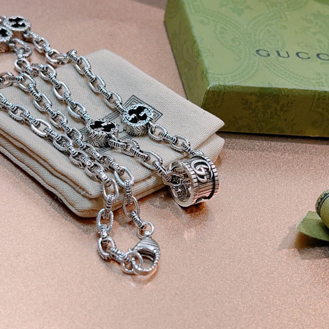 Silver-toned chain necklace with black enamel motifs and ring clasp on box