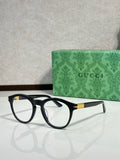 Black eyeglass frames with clear lenses and gold-tone logo detail on the temple