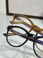 Gold-brown and black eyeglass frames overlapping, clear lenses visible