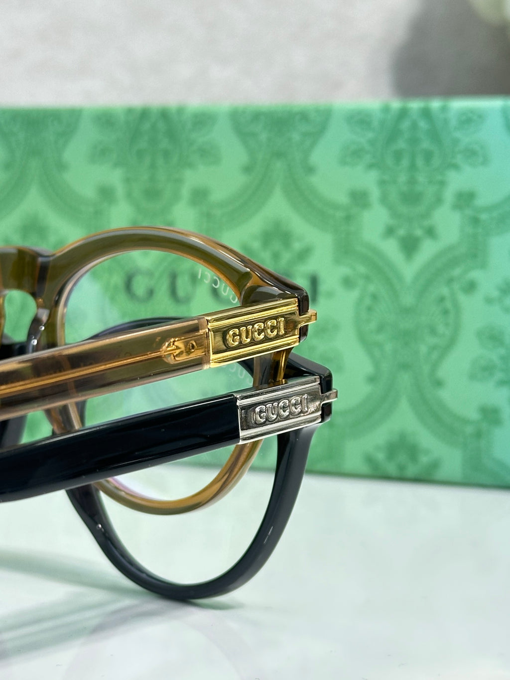 Gold-tone eyeglass temple with engraved logo detail on a brown frame