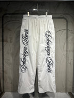 White track pants with elastic waistband, drawstring, and large vertical logo print