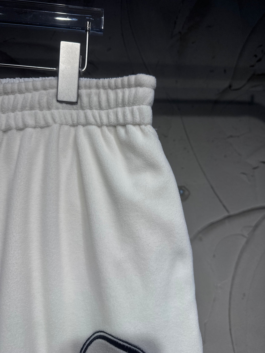 White elastic-waist track pants with gathered top and partial black logo at hem
