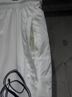 White track pants with front zip pocket and drawstring, elastic waist