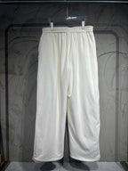 White track pants hanging on a hanger, elastic waistband and wide straight legs