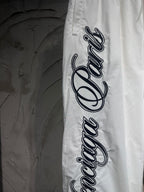 White track pants with oversized black logo lettering along the outer leg