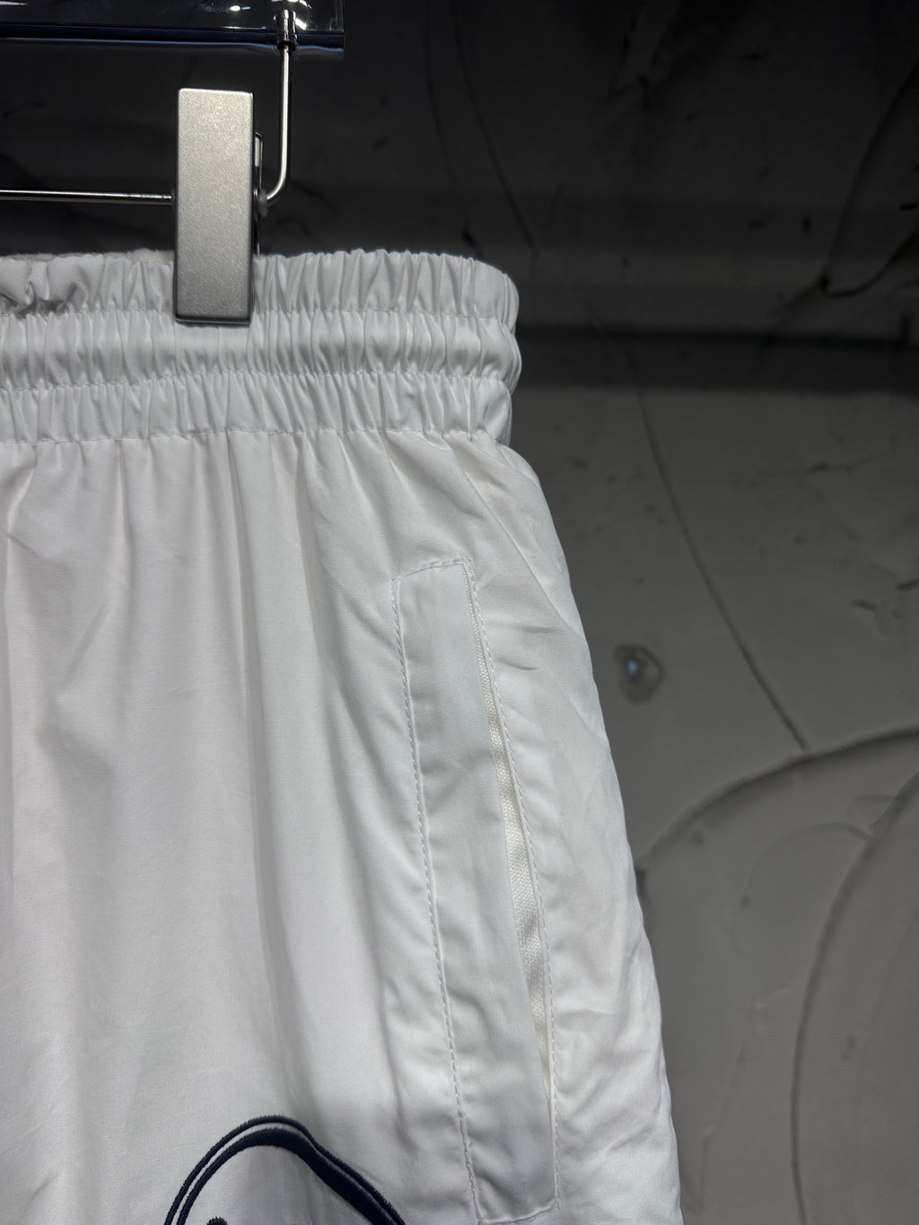 White track pants with elastic waistband and side seam stitching, relaxed fit